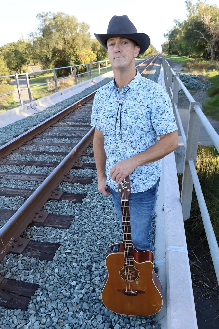 Shawn Wrangler standing by railroad tracks
